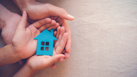 Kinder- und Jugendhilfe, Kinderhände, Erwachsene, Haus, Papier Kinderhände liegen in Händen von Erwachsenen, darin ein Haus aus Papier