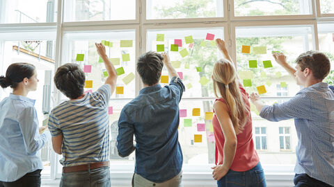 Karriere im HSL ein paar junge Menschen kleben bunte Postits auf Fensterscheiben